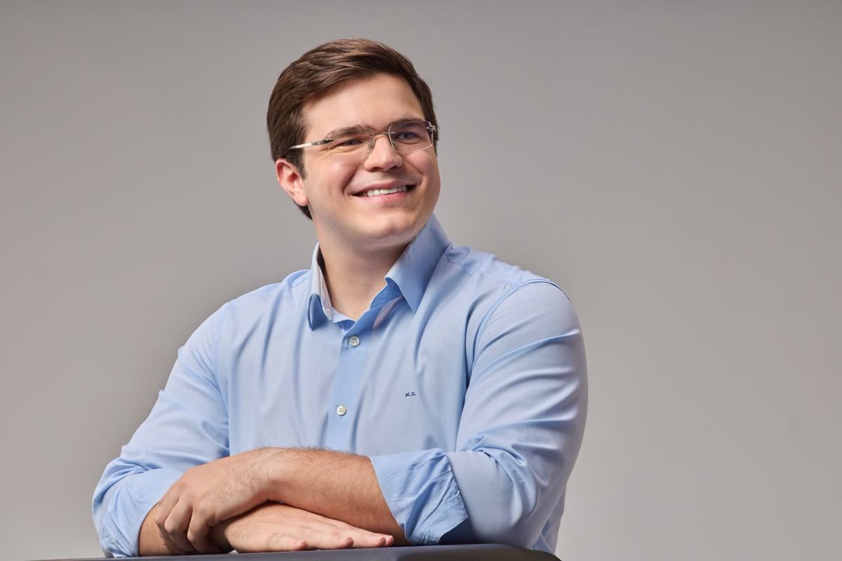 Miguel Duque sorrindo, de camisa azul